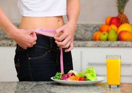 O fată care pierde în greutate după o dietă își măsoară talia